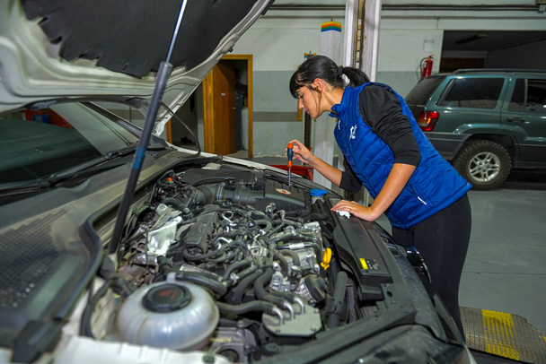 Young female mechanic, working on the repair of a car engine - Foto, imagen
