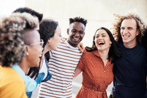 Młodzi szczęśliwi ludzie śmieją się razem. Różnorodny portret studentów kultury obchodzony na zewnątrz - Zdjęcie, obraz