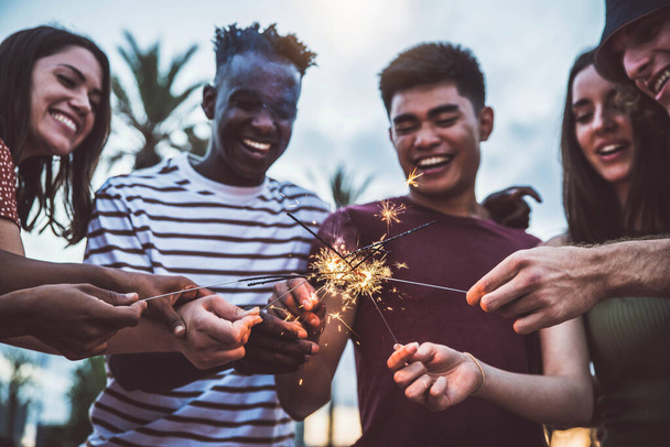 Multiraciale jongeren vieren feest met vuurwerk. Happy lifestyle, feestdagen, evenementen en feesten concept - Foto, afbeelding