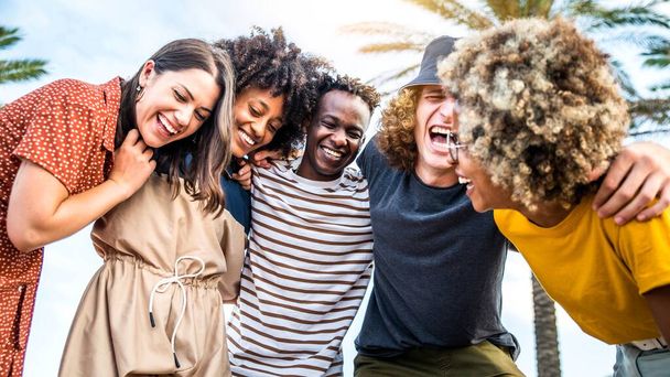 An einem sonnigen Tag lachen junge Menschen unterschiedlicher Rassen laut. Personalpolitik, Jugendstil und Sommerferienkonzept - Foto, Bild
