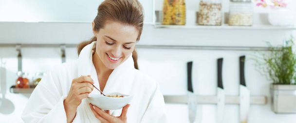 Усміхнена молода домогосподарка має здоровий сніданок на сучасній кухні
 - Фото, зображення