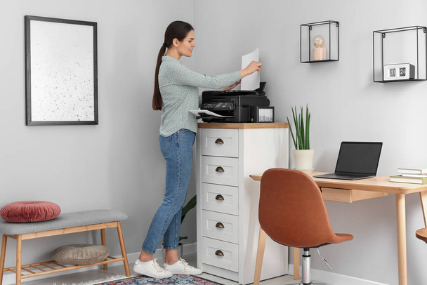 Woman using modern printer on chest of drawers at home - Foto, Imagem