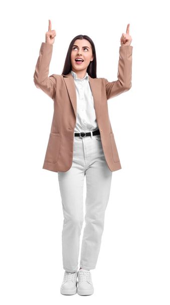 Beautiful businesswoman in suit pointing at something on white background - Valokuva, kuva