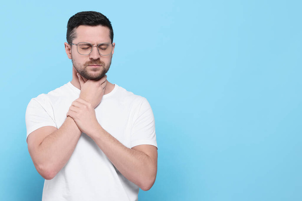 Man suffering from sore throat on light blue background, space for text - Фото, зображення
