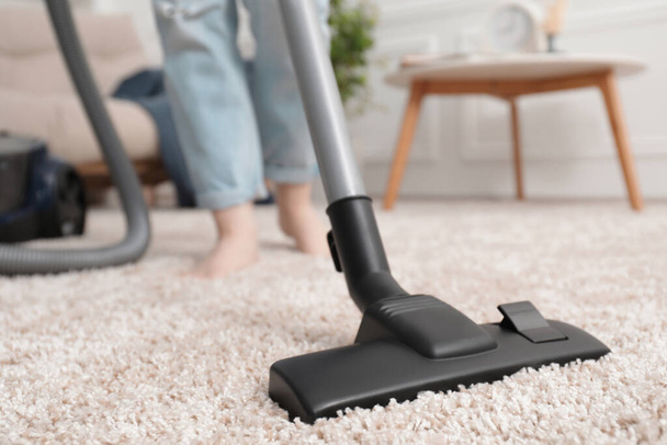 Woman cleaning carpet with vacuum cleaner at home, closeup - Photo, image