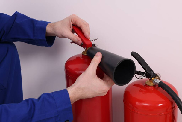 Man checking quality of fire extinguishers indoors, closeup - Foto, afbeelding
