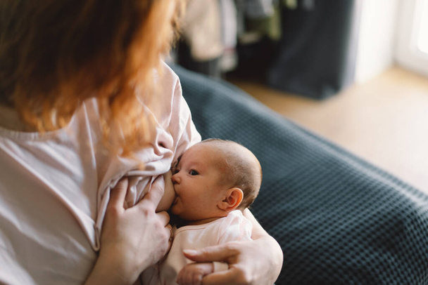 Newborn baby girl sucking milk from mothers breast. Portrait of mom and breastfeeding baby. Concept of healthy and natural baby breastfeeding nutrition. - Photo, Image