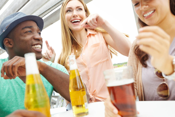 Letting loose on the weekend. A group of friends enjoying drinks on the deck of a trendy outdoors restaurant - Foto, Bild
