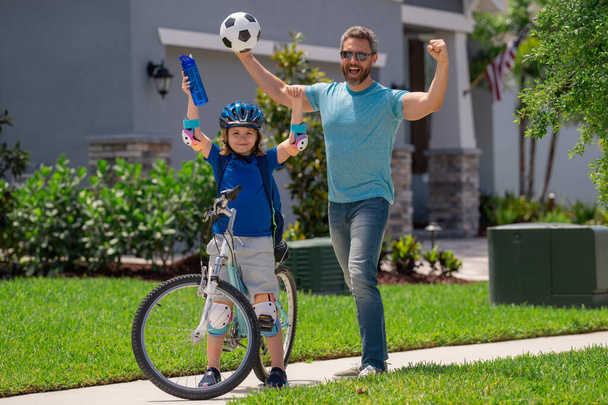 Fathers day. Happy family, men generations. Concept of friendly family and summer lifestyle. Sporty family. Excited father and son with winning gesture. Parents and children friends. Child first bike - Fotó, kép