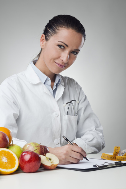 Smiling nutritionist writing medical records - Foto, Imagem