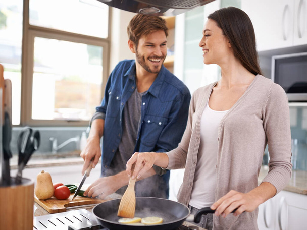 Happy couple, food and cooking together in a pan in the kitchen with healthy organic ingredients for dinner at home. Man helping woman with smile in happiness making meal with vegetables on stove. - Φωτογραφία, εικόνα