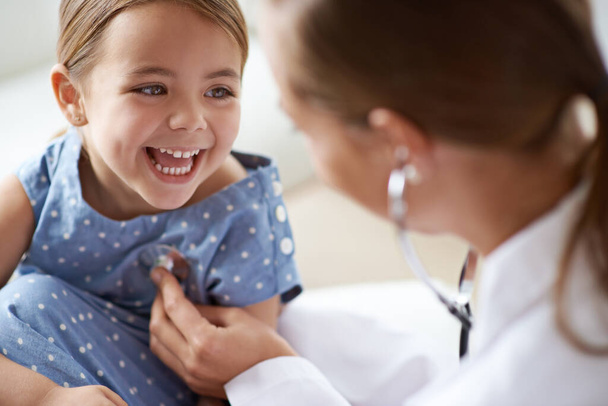 Happy child, girl and stethoscope of doctor for medical consulting, healthy lungs and listening to heartbeat. Face of laughing kid, pediatrician and chest assessment for healthcare analysis in clinic. - Фото, зображення