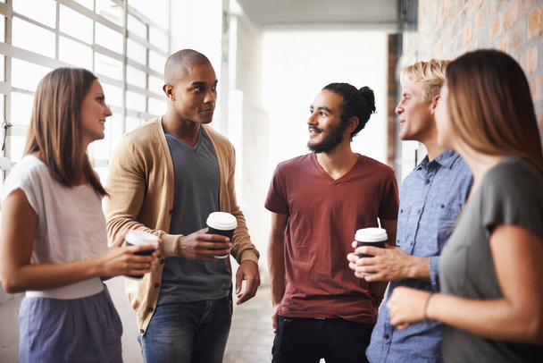 Колледж, друзья и беседа с кофе в коридоре для разнообразия, счастья и напитков. Группа мужчин и женщин студентов кампуса или университета для беседы или разговора о карьере в сфере образования. - Фото, изображение