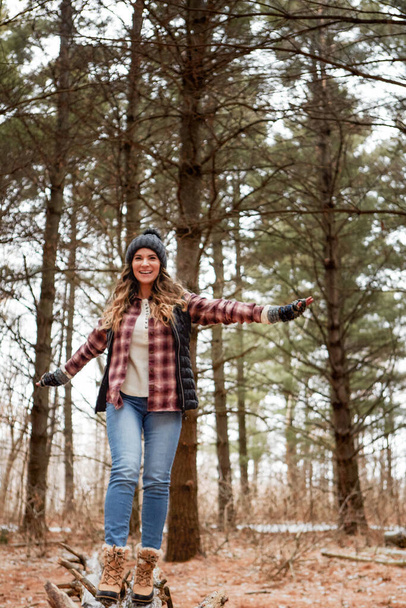 Let hope and optimism flow through you. a young woman walking on a tree log in the wilderness during winter - Photo, Image