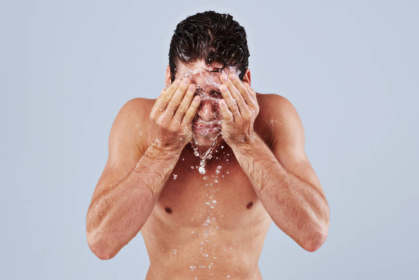 Окончательное очищение. Студийный снимок голого молодого человека, плескающего водой в лицо - Фото, изображение