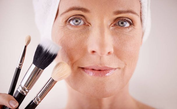 Which one is the most important. Portrait of a beautiful mature woman posing with a set of makeup brushes - Photo, image