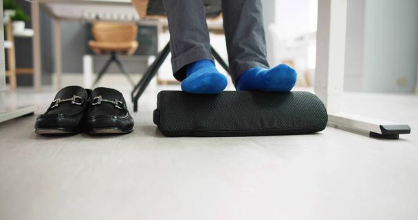 Man Using Footrest To Reduce Back Strain And Feet Fatigue - Fotografie, Obrázek