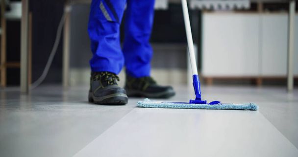 Portret szczęśliwego woźnego sprzątanie podłogi w biurze - Zdjęcie, obraz