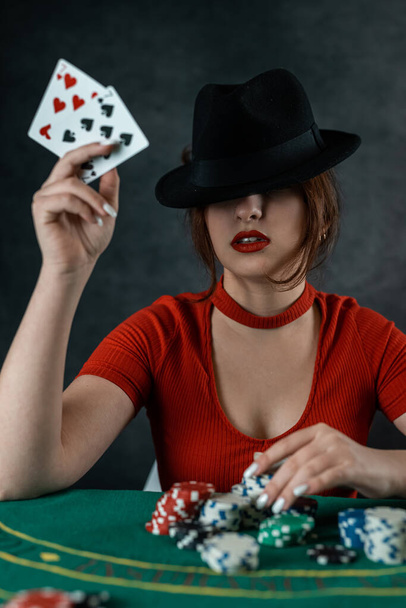 woman's hand takes poker cards at a round green poker table. risky bets in poker. woman in poker casino - Photo, image