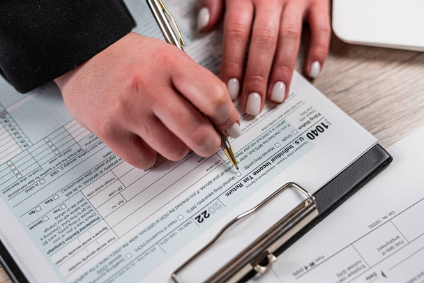 mujer de primer plano llenando 1040 formulario de impuestos en la oficina. concepto contable plazo - Foto, imagen