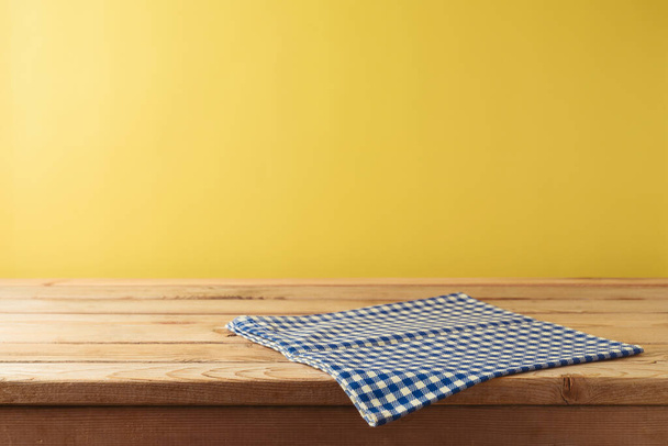 Brazilian Festa Junina summer harvest festival concept. Empty wooden table with tablecloth over yellow background. Mock up for design and product display - Fotoğraf, Görsel