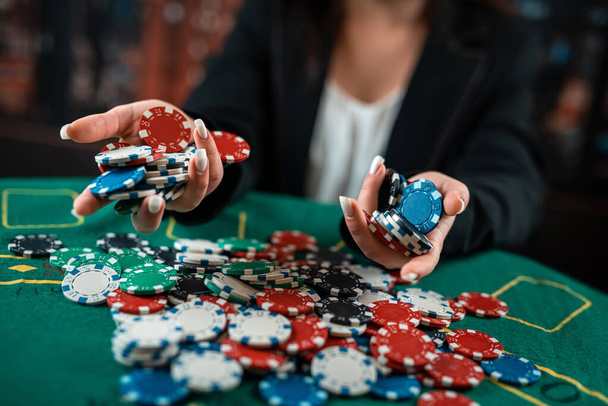 дівчина в червоній сукні показує кілька різнокольорових позуючих покерних фішок. Покер. казино. Близько
 - Фото, зображення