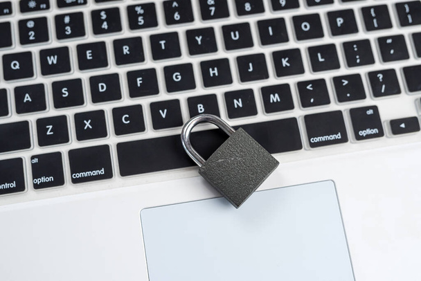 Black lock on the white laptop keyboard close up. Cyber safety concept.  - 写真・画像