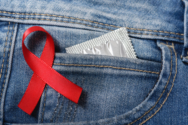 Red ribbon over blue denim with condom in pocket - Foto, immagini