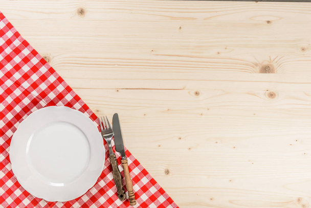 Fa asztal kockás piros asztalterítő lemez villa és kés - Fotó, kép