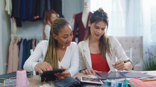 Dva profesionální asijské a africké americké ženy módní návrhářka pomocí tabletu drewing vzor pro design oblečení v obchodě s oděvy - Fotografie, Obrázek
