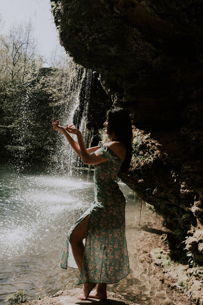 Hermosa modelo en un vestido turquesa posando cerca de una cascada de montaña.Concepto de vida silvestre - Foto, imagen