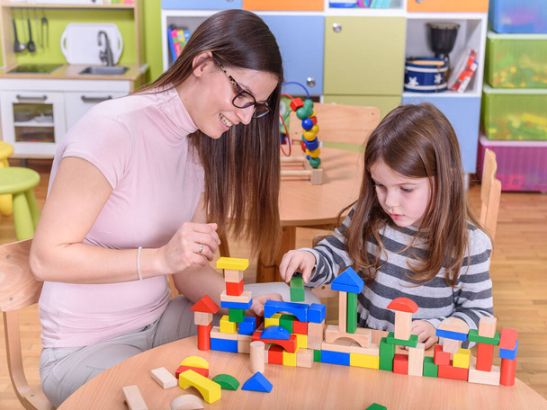 учитель и девочка играют с игрушечными блоками в школе - Фото, изображение