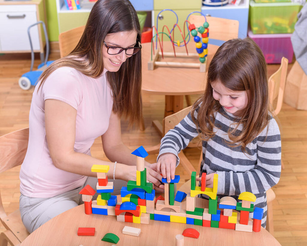 Öğretmen ve kız okulda oyuncak bloklarıyla oynuyor. - Fotoğraf, Görsel