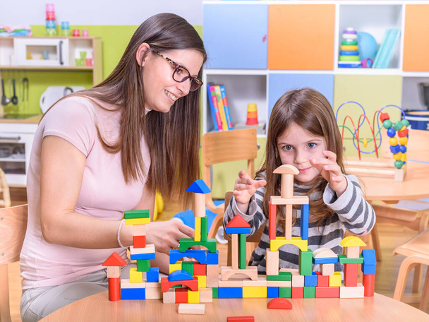 nauczyciel i dziewczyna bawią się klockami zabawek w szkole - Zdjęcie, obraz