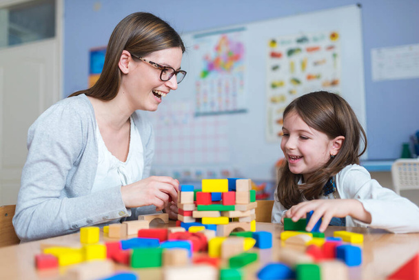 szczęśliwy nauczyciel i dziecko bawiące się klockami zabawki w domu - Zdjęcie, obraz