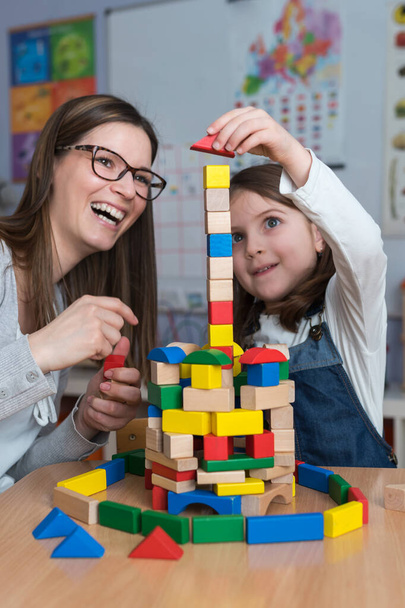happy teacher and kid playing with toy blocks at home - 写真・画像