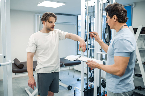 Physical therapy. Male patient have a physical therapy session in rehabilitation center - 写真・画像