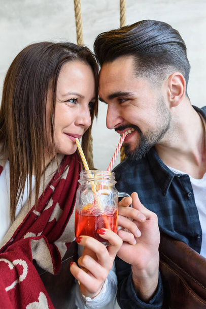 Young Love Couple in Cafe, Drinking from the same Glass with Straws - Photo, Image