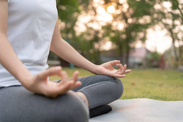 Nainen meditoi puistossa. Aasialainen nainen tekee harjoituksia aamulla. tasapaino, virkistys, rentoutuminen, rauhallinen, hyvä terveys, onnellinen, rentoutua, terveellinen elämäntapa, vähentää stressiä, rauhallinen, Asenne. - Valokuva, kuva