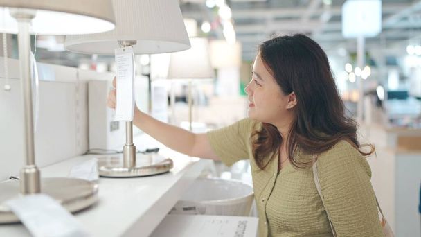 Heureuses femmes asiatiques acheter une lampe et l'essayer dans un magasin de meubles - Photo, image