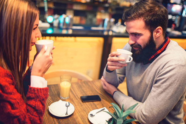 Beautiful couple drinking coffee talking and having fun in cafeteria - Foto, imagen