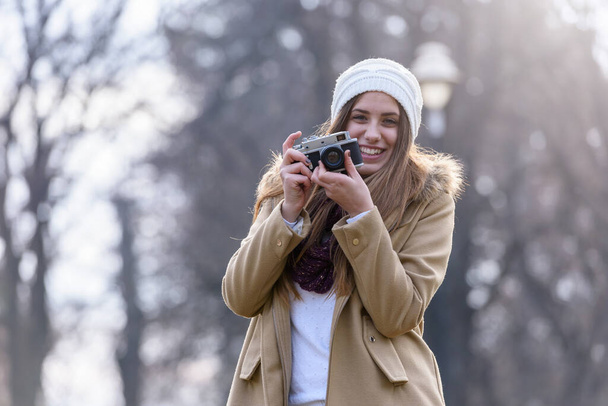 Retrato de niña de invierno tomando fotos con cámara vintage - Foto, imagen