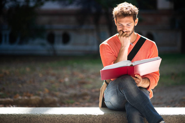 Yakışıklı genç adam parkta bankta kitap okuma - Fotoğraf, Görsel