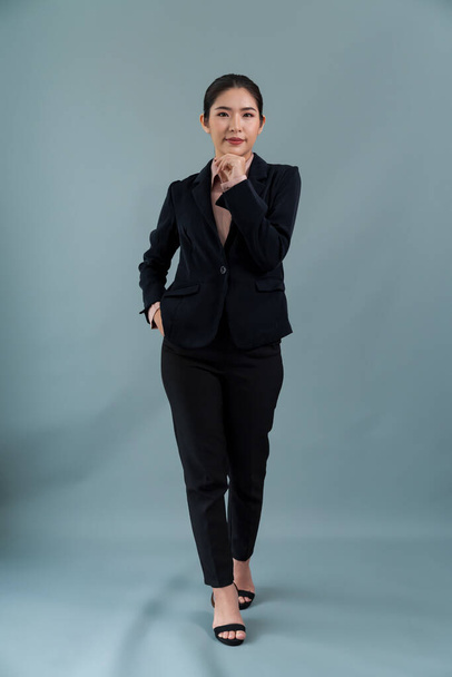 Full body length image of confident young businesswoman stands on isolated background, posing in formal black suit. Office lady or manager with smart and professional appearance. Enthusiastic - Foto, Imagem