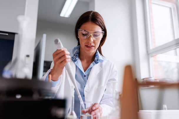 női tudós a laboratóriumban, aki kémiai vizsgálatokat végez - Fotó, kép