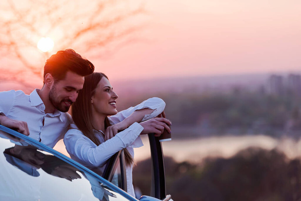 Ρομαντικό ζευγάρι στο ηλιοβασίλεμα που ταξιδεύουν με αυτοκίνητο - Φωτογραφία, εικόνα