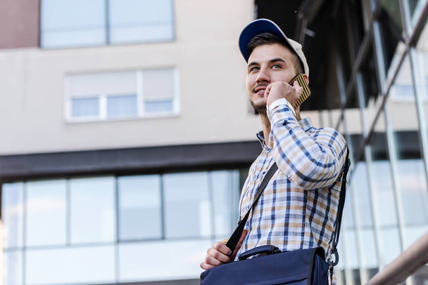 Молодой человек с мобильным телефоном на улице
  - Фото, изображение