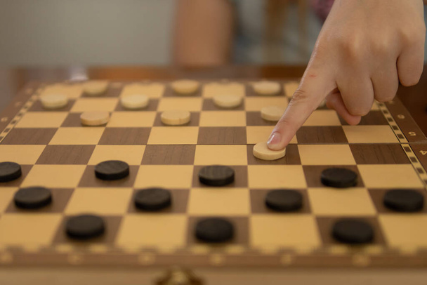 close-up of a girls hand playing checkers, non-lectual games for a teenager. High quality photo - Фото, изображение