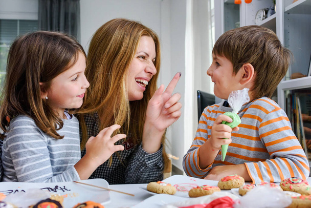 Mother with children decorating cookies for Halloween celebration - Zdjęcie, obraz
