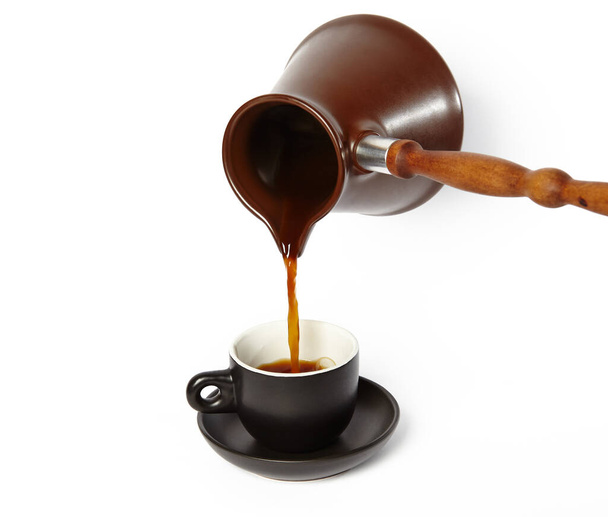 Man pouring coffee into cup isolated white background. Clay cezve for making coffee in the hand - Φωτογραφία, εικόνα